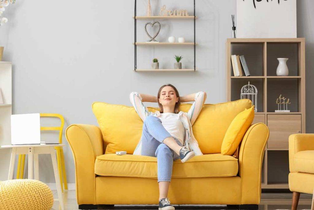 Young Woman Relaxing On Sofa In Living Room